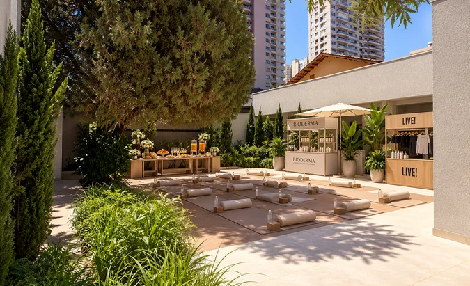 Imagem conceitual do jardim montado com ativações de marcas, mesa de brunch e tapetes de treino