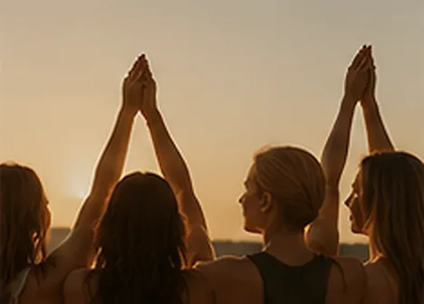 Mulheres com as mãos unidas para o alto ao pôr do sol